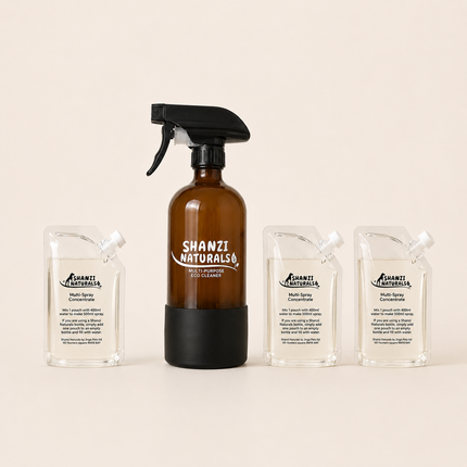Shanzi Naturals eco cleaner set with a brown spray bottle and three clear containers on a beige background